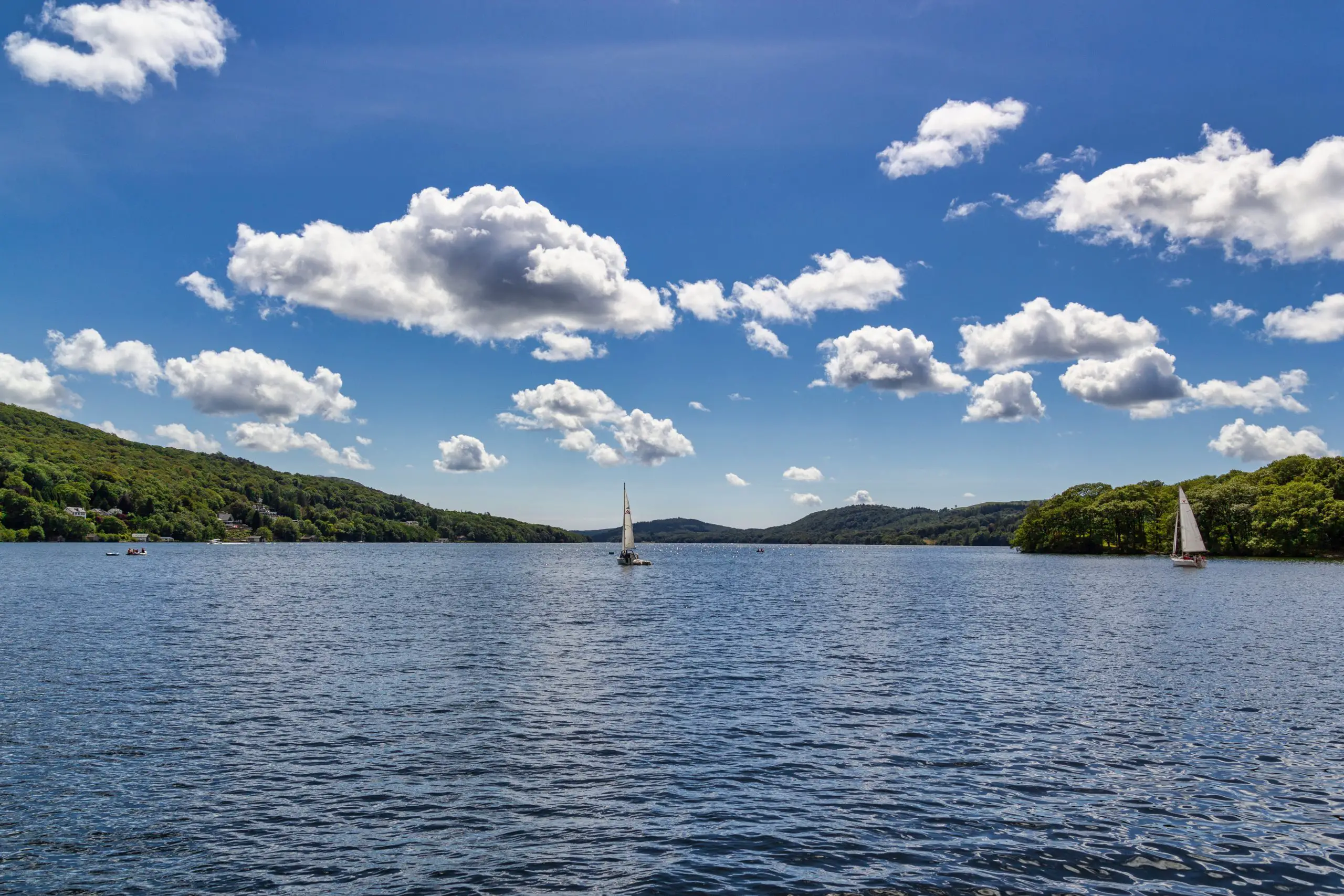 Boats in the Windermere lake with little fluffy clouds above